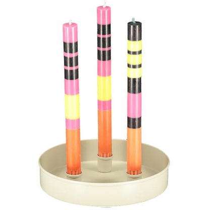 A small round powder-coated steel candle platter in a natural shade of soft white with 3 metal cups to hold dinner or taper candles, featuring 3 multi-colored abstract dinner candles